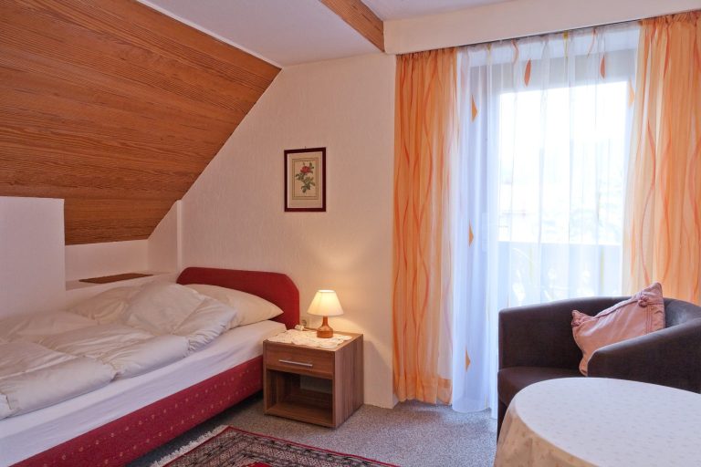 Helles Schlafzimmer mit einem Einzelbett, Balkon mit Bergblick.